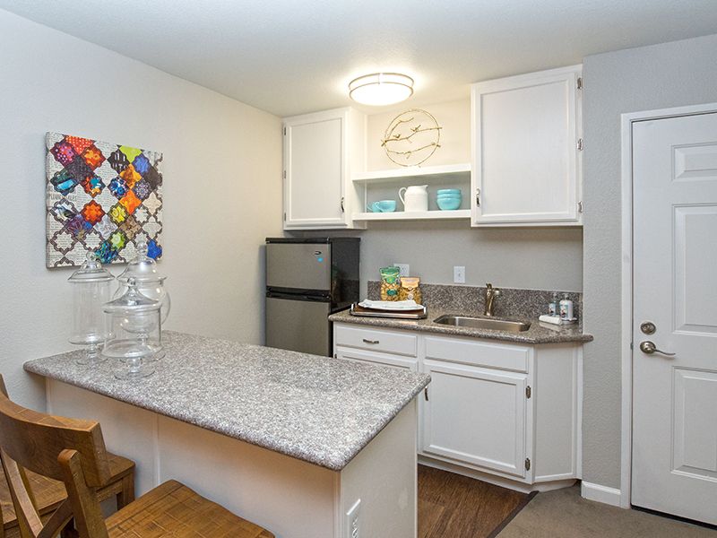 A compact and modern kitchen with white cabinetry and stainless steel appliances.