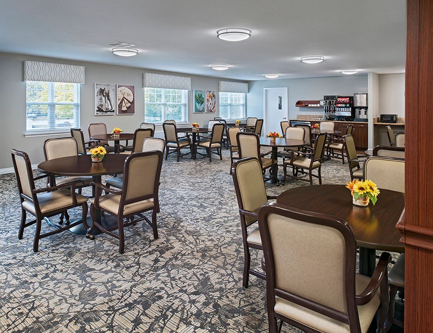 A well-lit dining room with neatly arranged tables and chairs, featuring stylish decor and large windows.