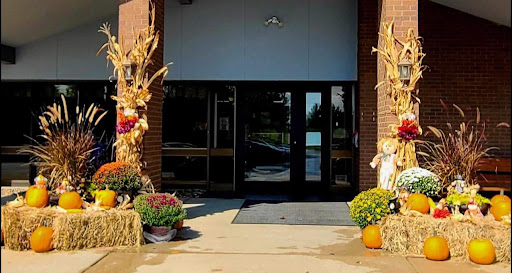 A welcoming entrance adorned with autumn decorations, featuring vibrant flowers and cornstalks.
