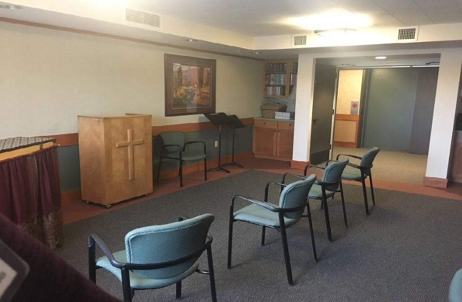 A small chapel with a few chairs and a podium featuring a cross.