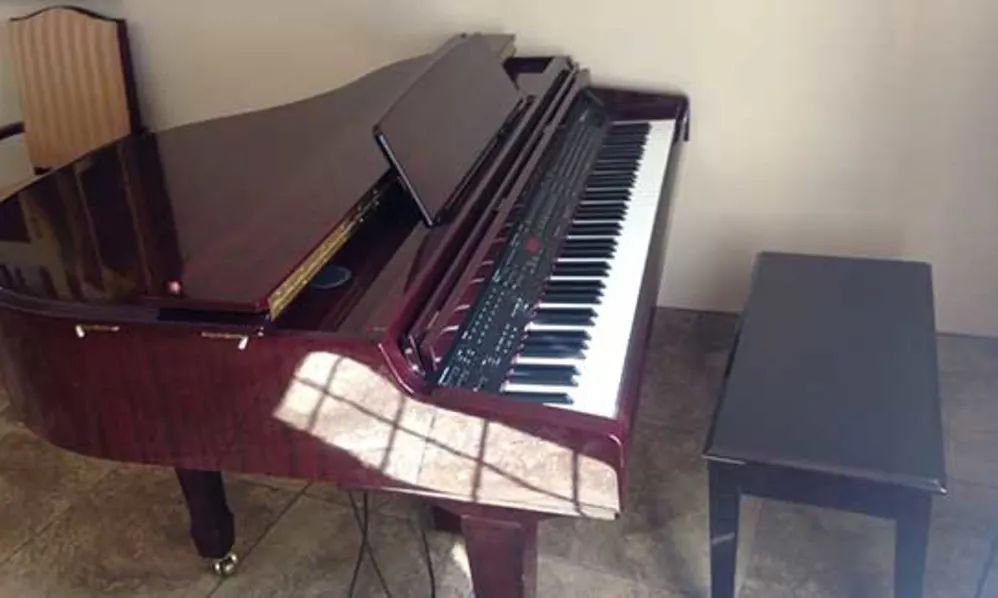 A digital keyboard with a grand piano design in a room.