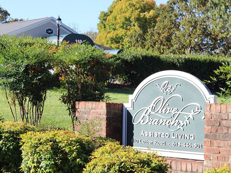 Entrance sign for a senior living community surrounded by greenery.