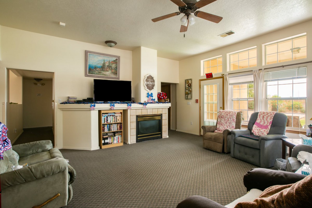 A cozy living room featuring a sofa, fireplace, and television, with natural light streaming through the windows.