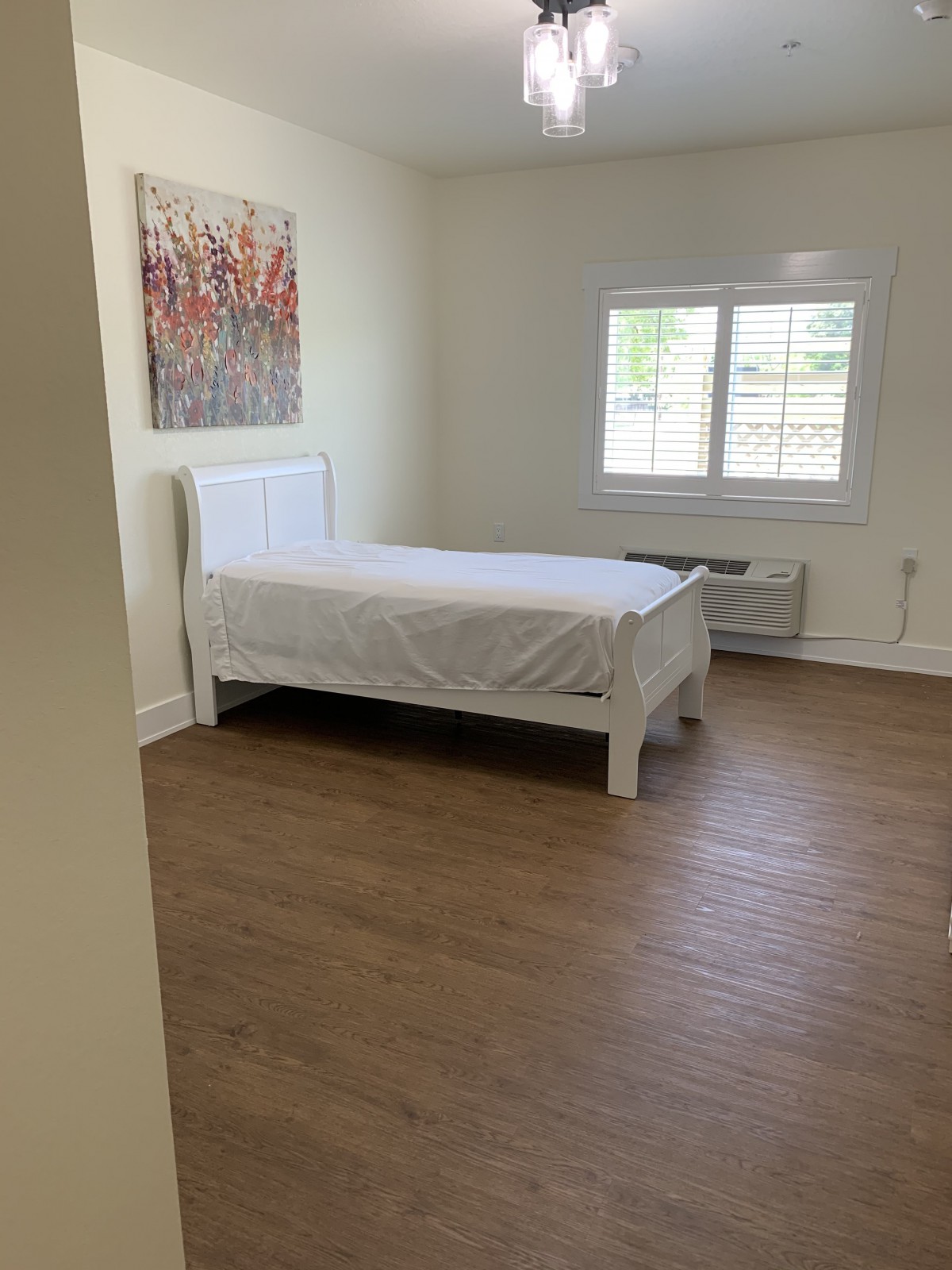 A minimalist bedroom with a single bed and wooden flooring.