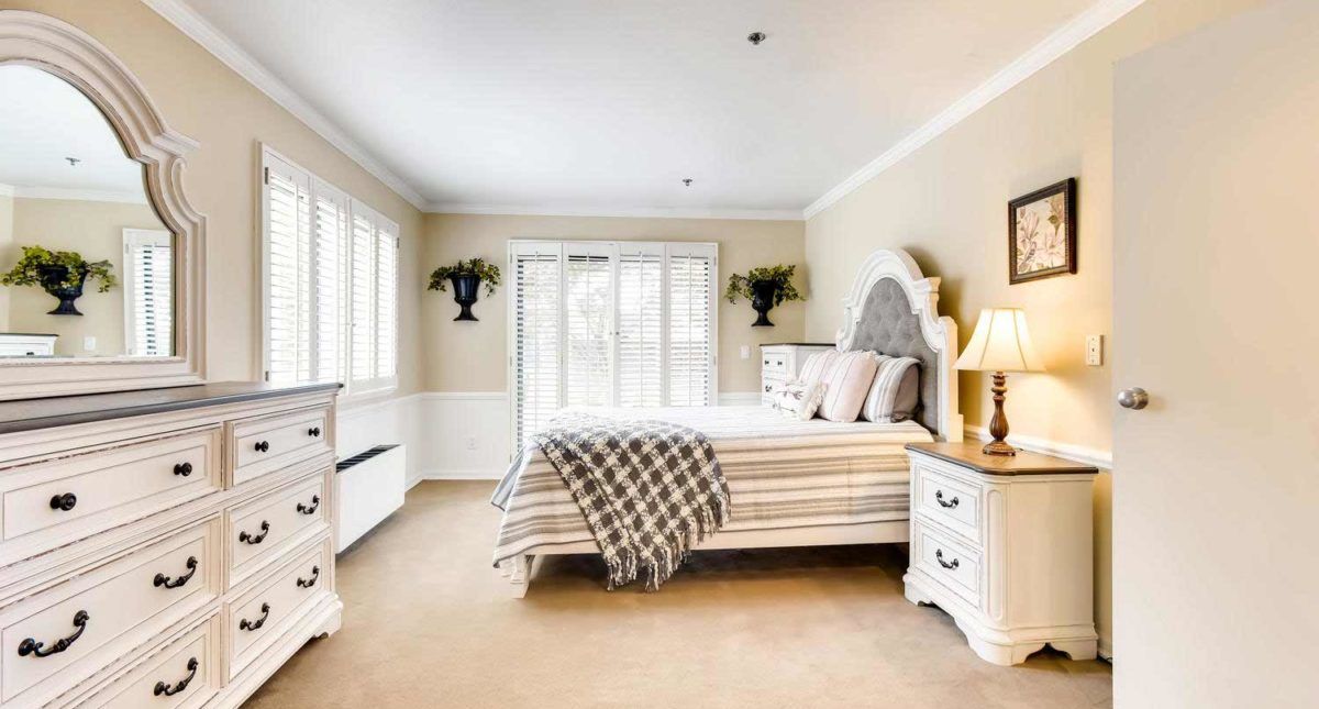 A bright and elegant bedroom with classic decor, featuring a comfortable bed, stylish furniture, and abundant natural light.