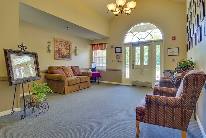 A cozy living room with a sofa, chairs, and a large window letting in natural light.