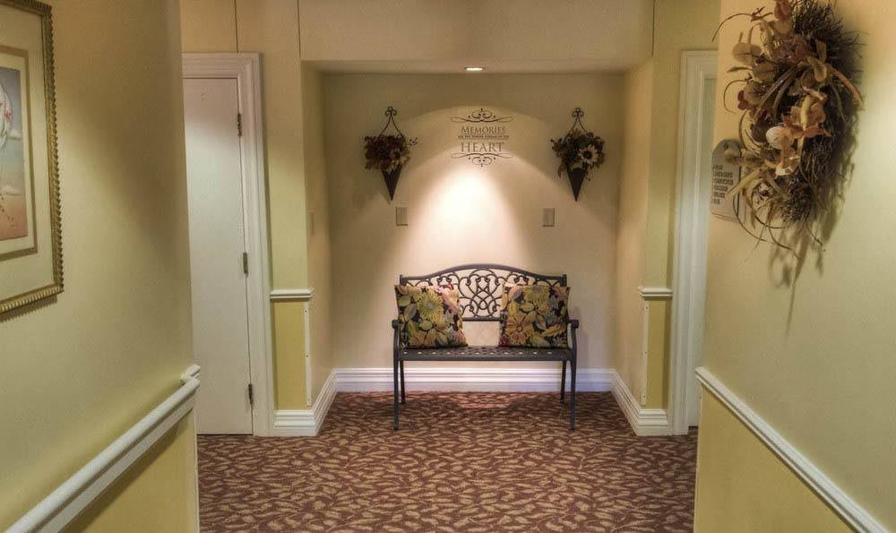 A cozy hallway featuring a decorative bench with floral pillows, flanked by wall ornaments and soft lighting.