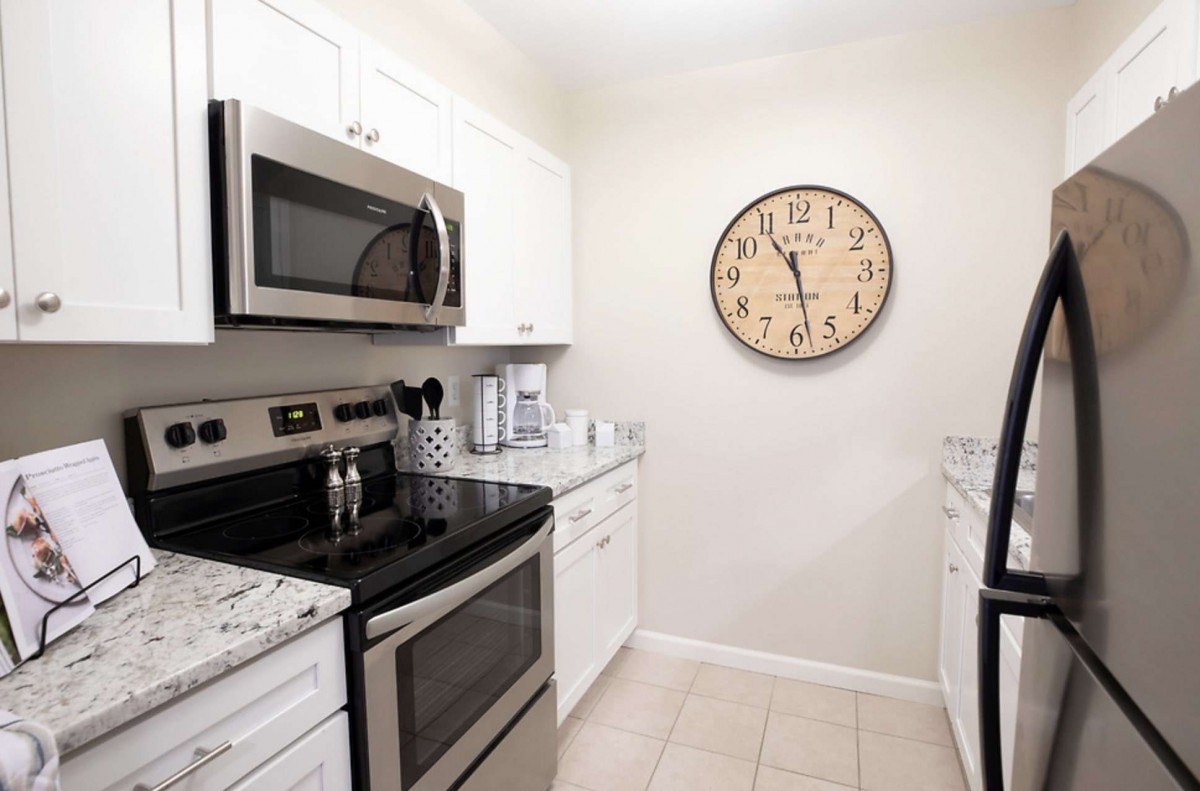 Modern kitchen with stainless steel appliances and a large wall clock.