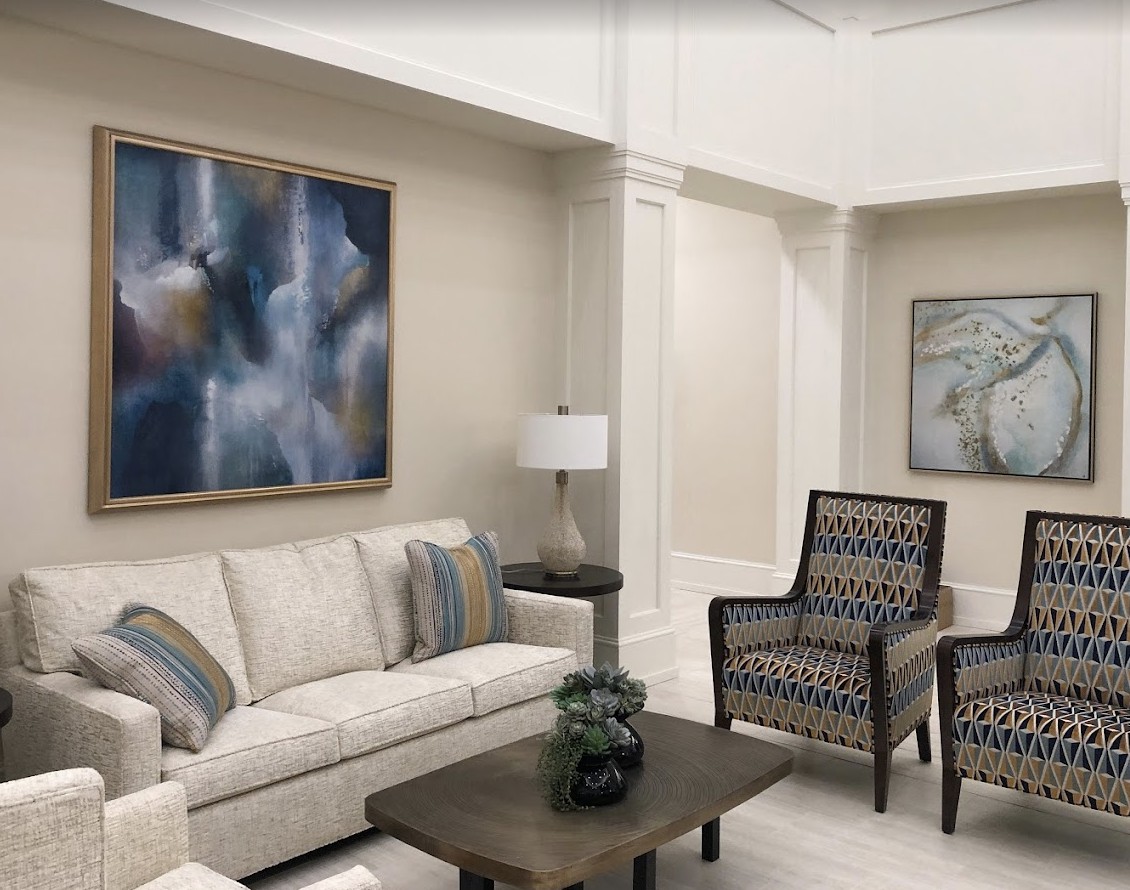 A stylish and modern living room with a sofa, armchairs, coffee table, and abstract artwork on the walls.