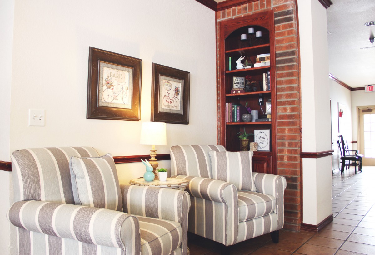 A cozy living room corner featuring striped chairs, a lamp, and built-in shelves with decor.