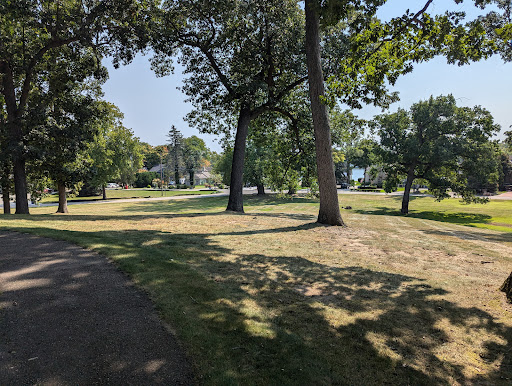 A serene view of a park with lush trees and open grassy areas.