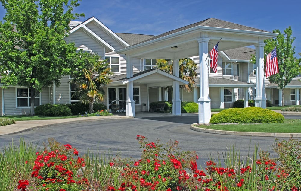 A residential building with a landscaped entrance and blooming flowers.