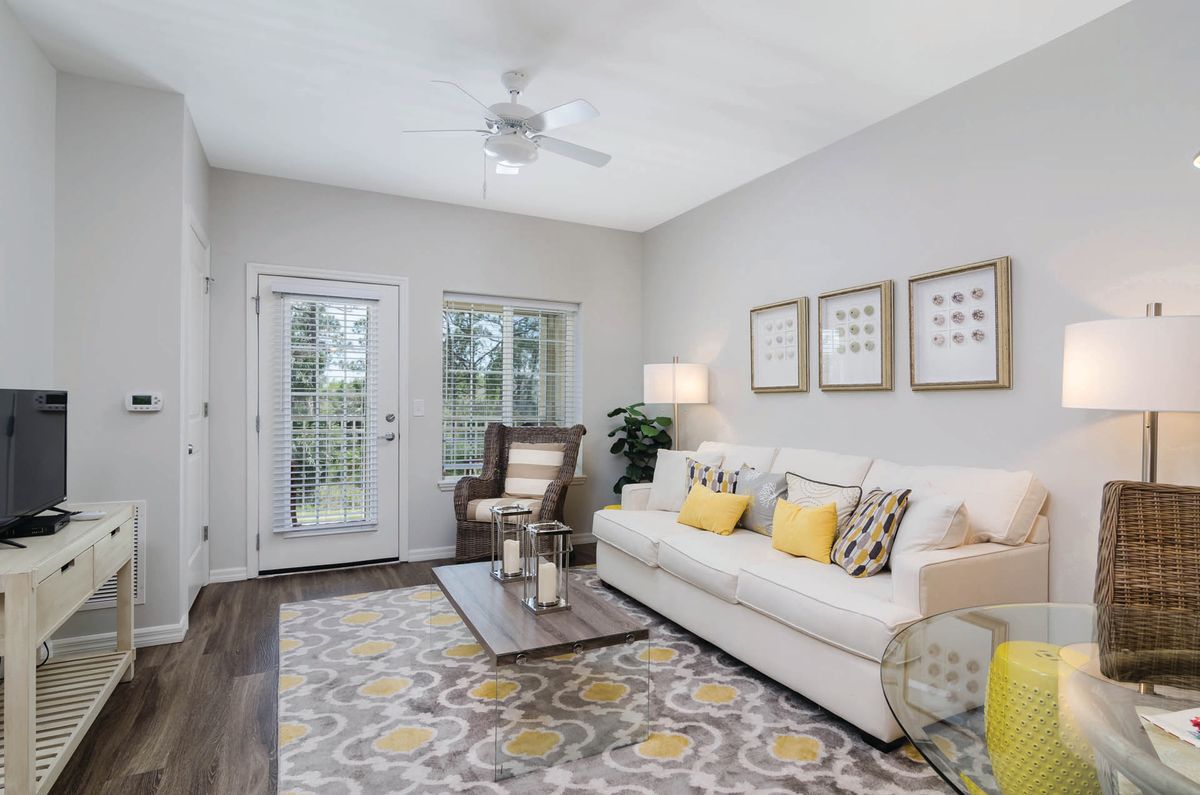 A cozy living room with a neutral color palette, featuring a sofa, patterned rug, armchair, and decorative elements.