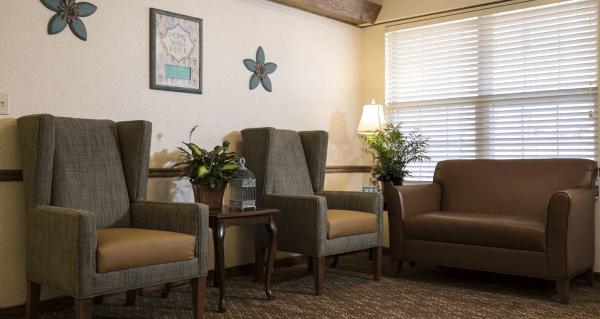 A cozy living room with comfortable chairs, plants, and warm lighting.