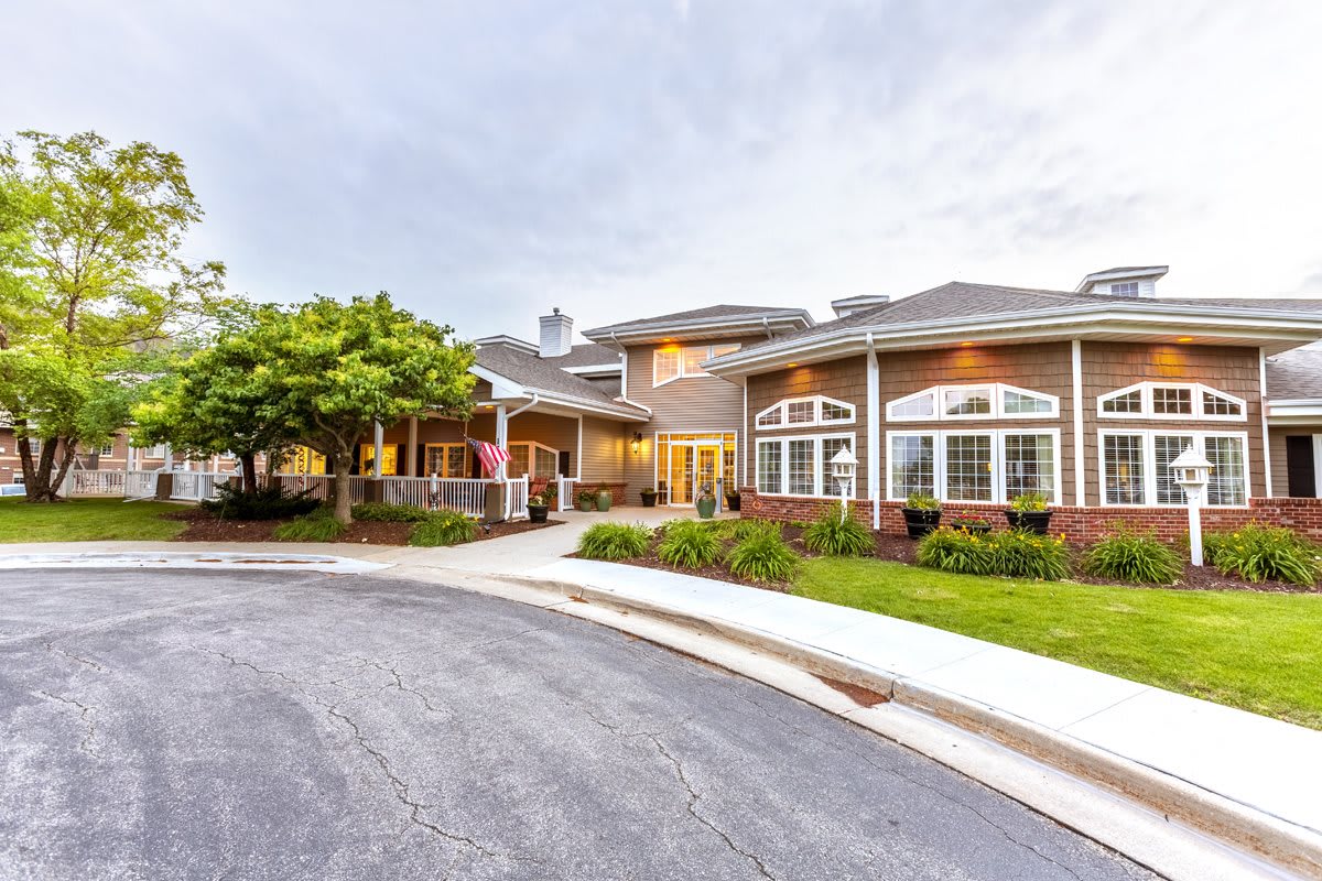 A view of a house with a driveway and surrounding trees.