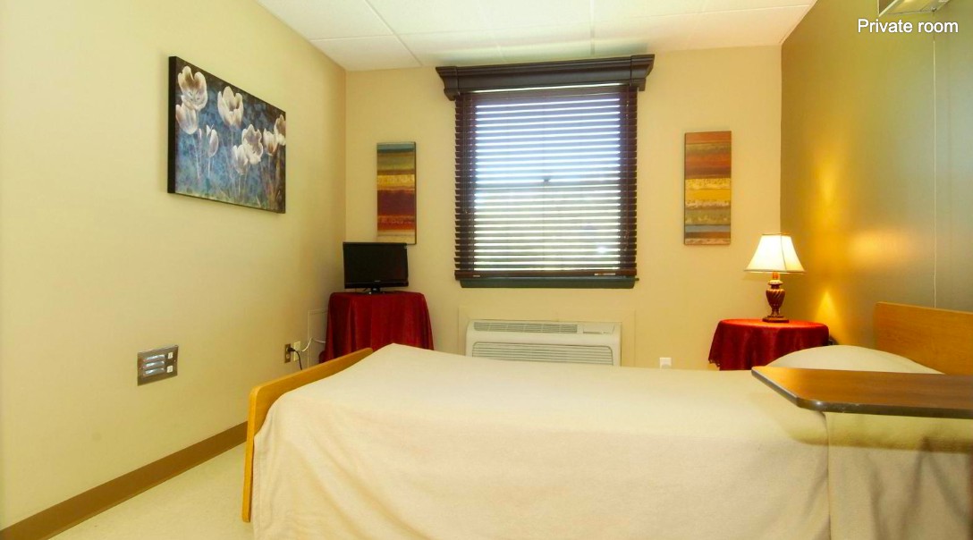 A cozy bedroom with a bed, artwork on the walls, and a window with blinds.