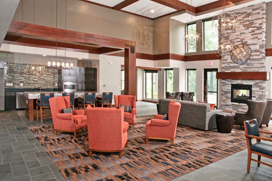 A modern lounge area with orange armchairs and large windows.