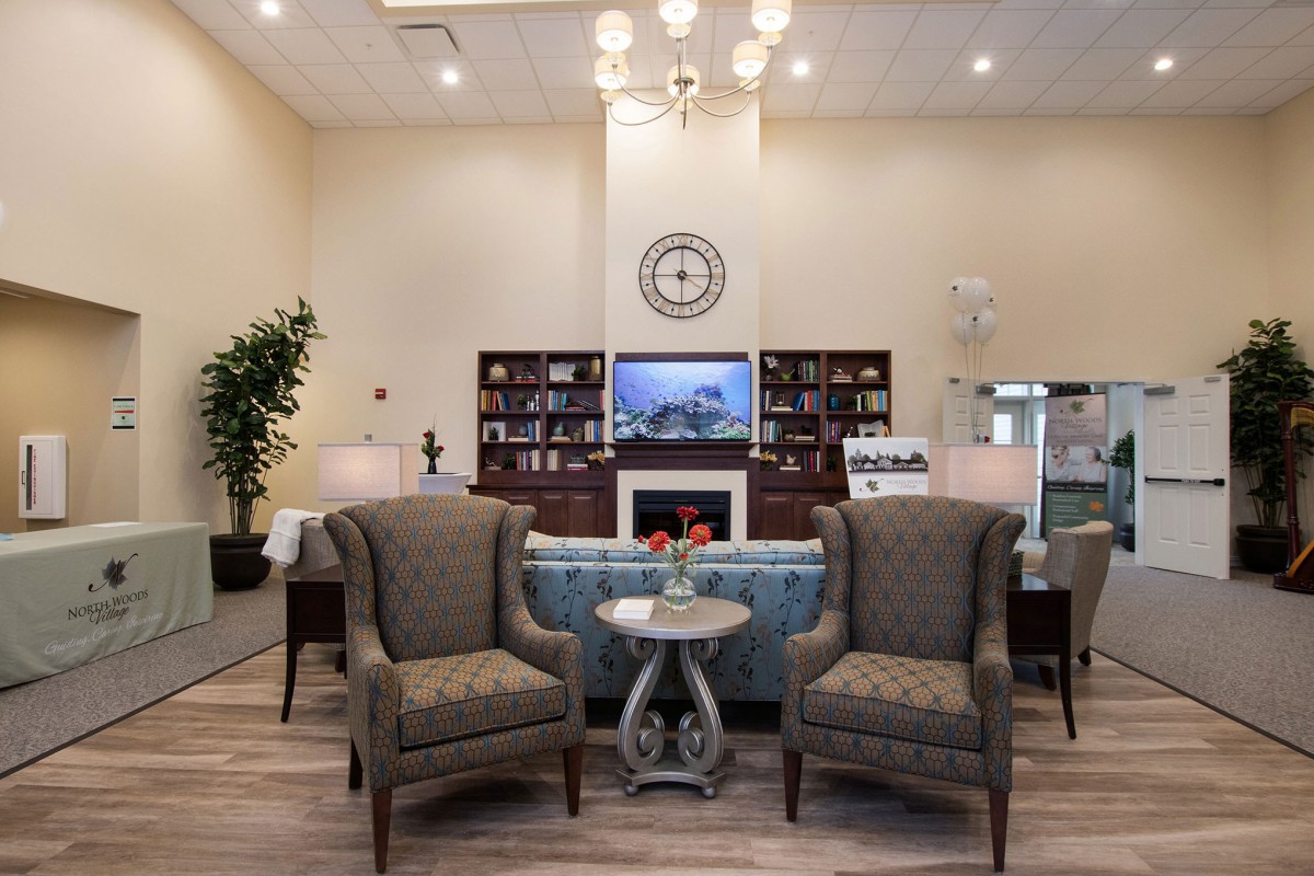 A cozy living room with elegant armchairs, a decorative fireplace, and a well-stocked bookshelf.
