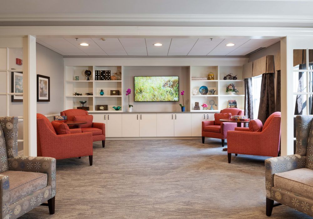 A cozy living room with orange armchairs and a television surrounded by shelves.