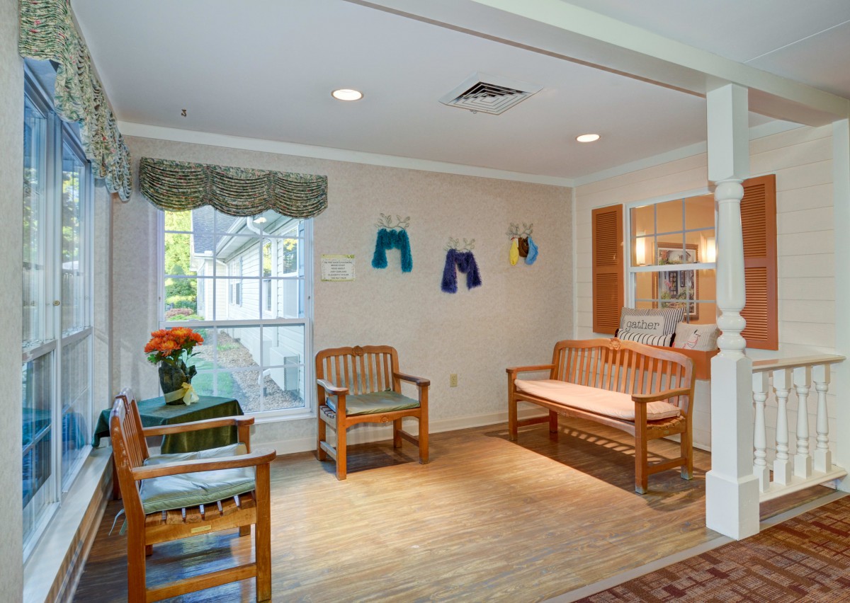 A cozy waiting room with wooden benches, colorful wall decor, and a vase of flowers.