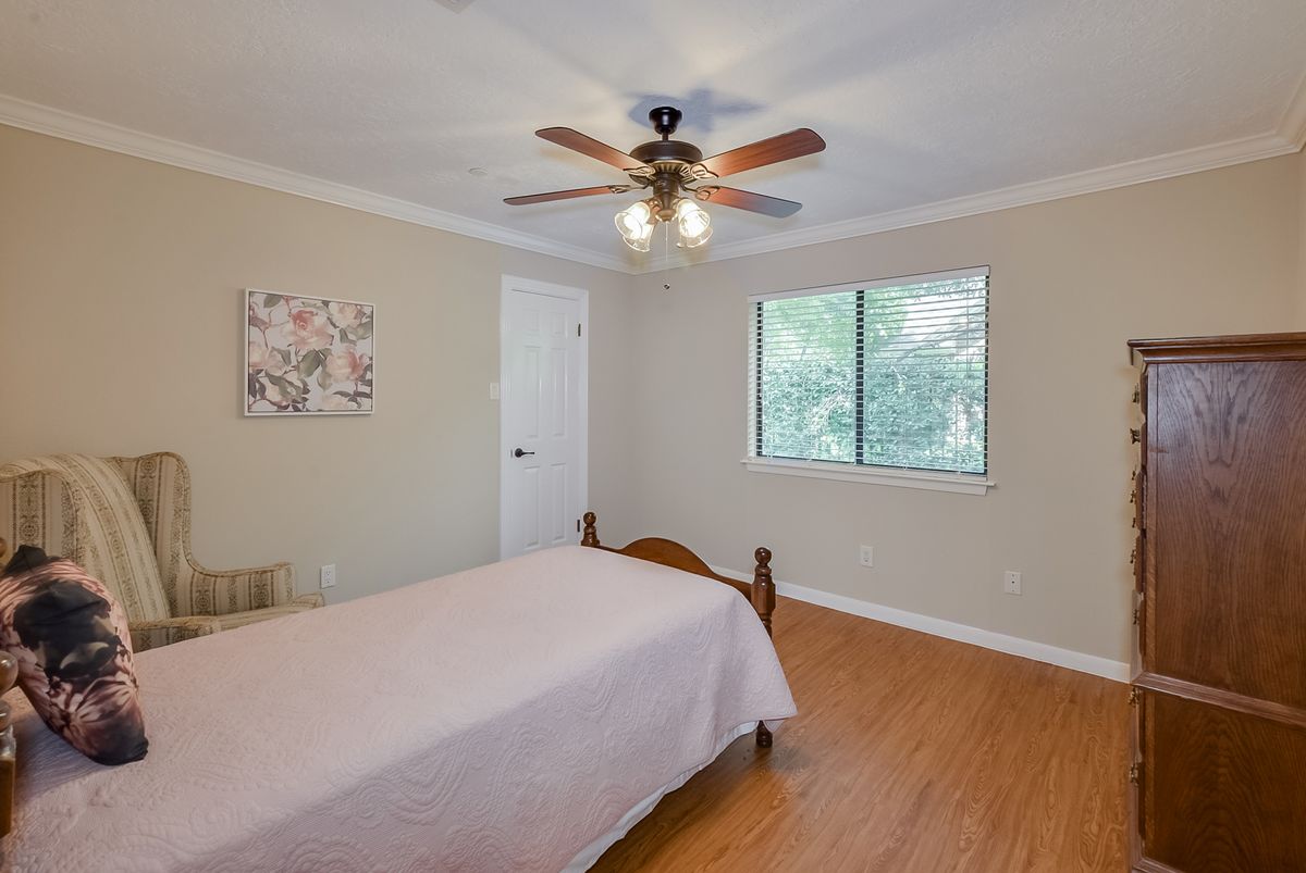 A cozy bedroom with a single bed, ceiling fan, and hardwood flooring.