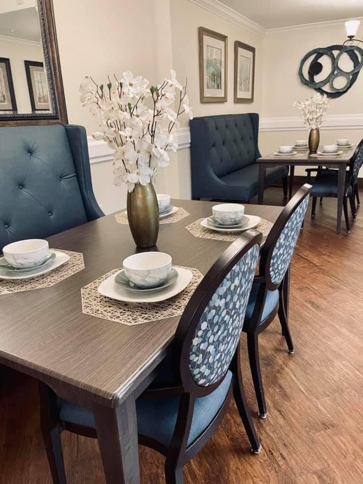 A cozy and elegant dining room with blue upholstered chairs and a well-arranged table setting.