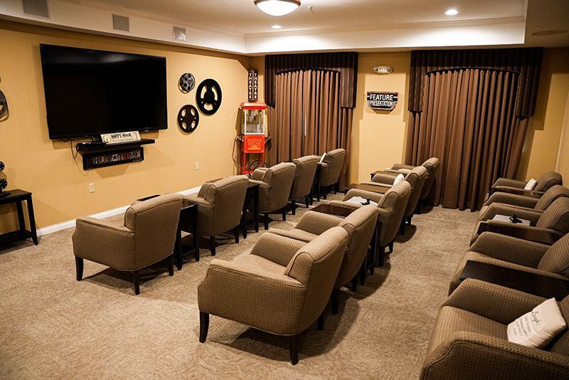 A cozy home theater with comfortable seating, a large screen, movie-themed decor, and a popcorn machine.