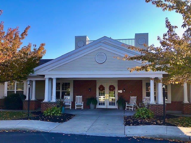 A welcoming building entrance with columns and a porch, framed by landscaping.