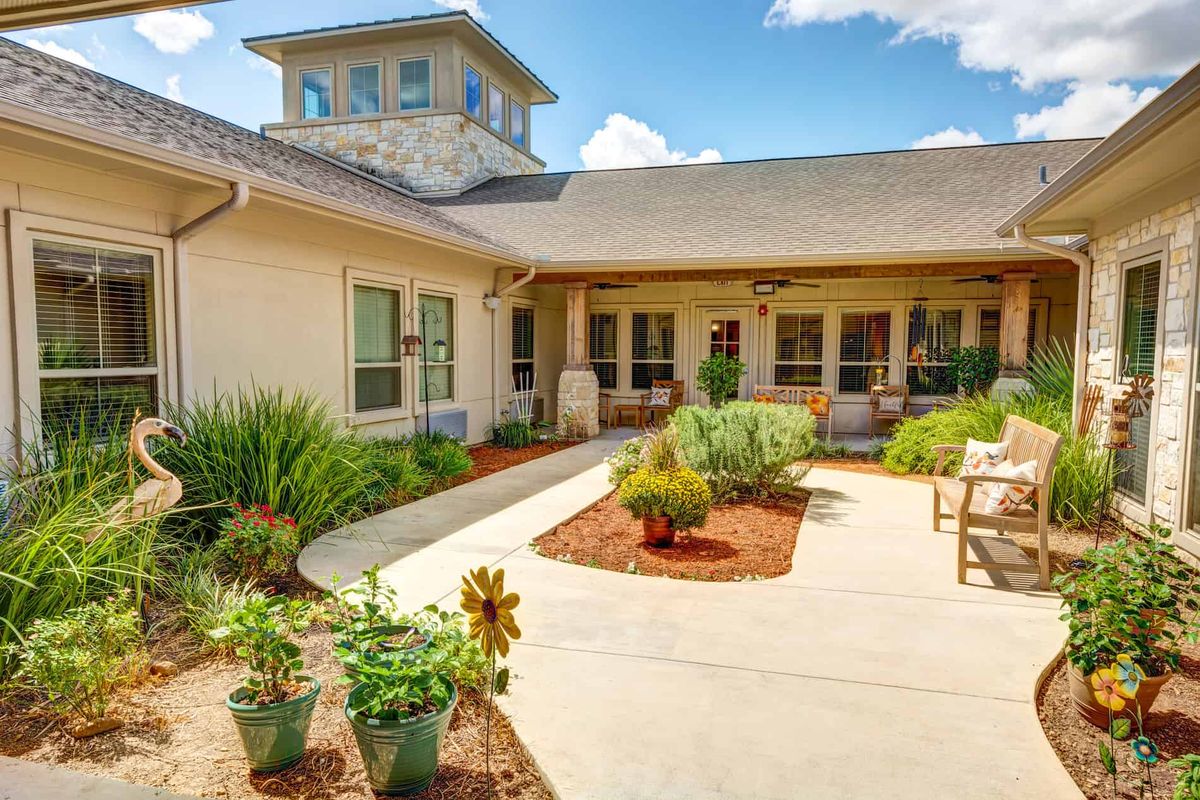 A peaceful courtyard garden with lush greenery and a seating area, adjacent to a building.