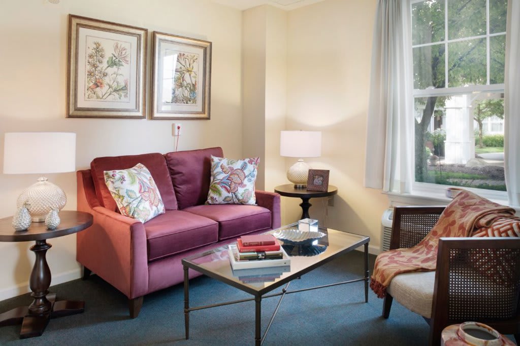 A cozy living room with a red sofa, colorful cushions, a glass coffee table, and elegant decor.