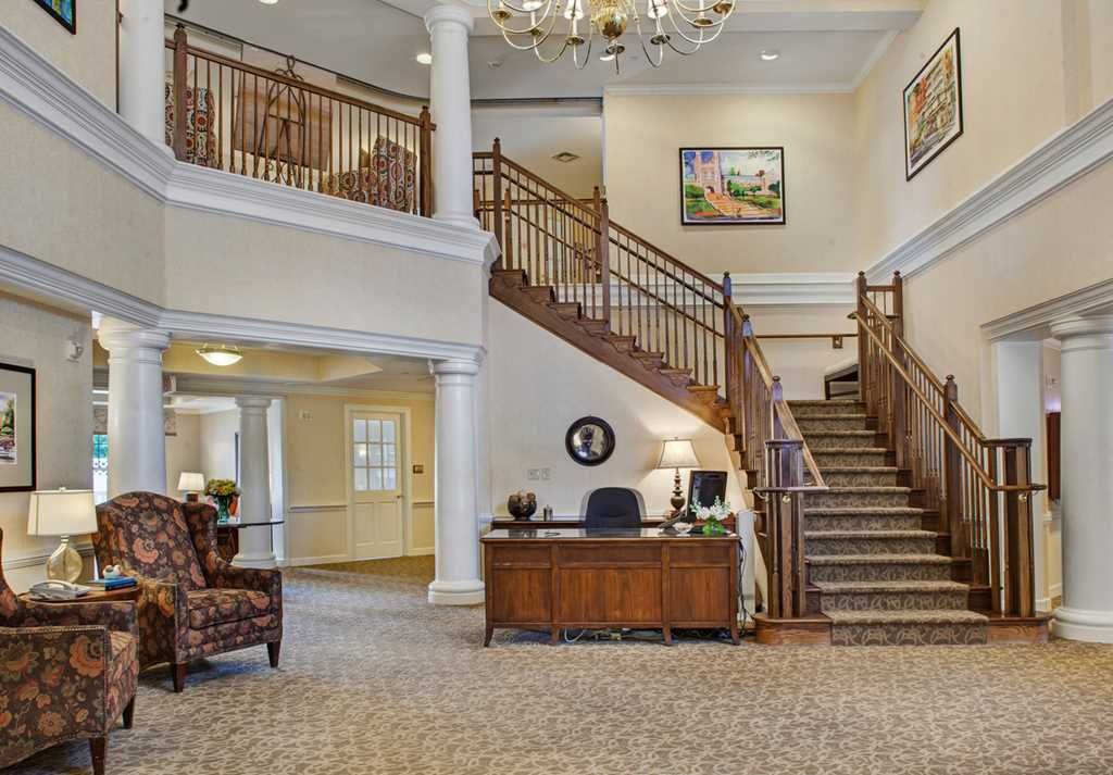 A spacious lobby with a grand staircase, chandelier, and reception desk.