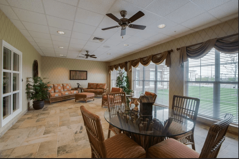 A spacious living room with comfortable seating, ceiling fans, and large windows.