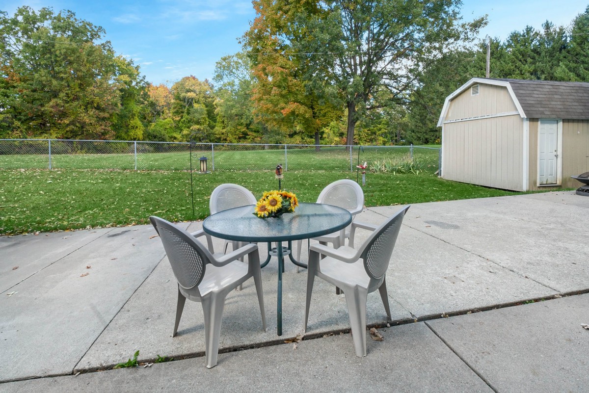 A tranquil backyard patio with a glass table and four chairs, perfect for outdoor relaxation.