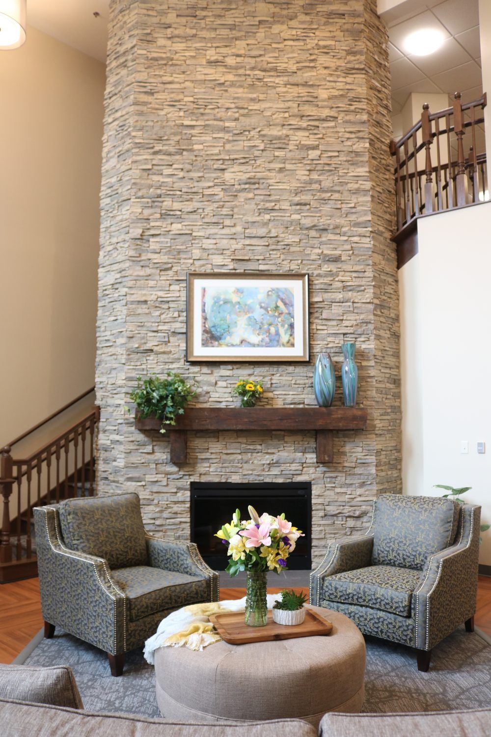 A cozy living room with a stone fireplace, decorated with art and plants.