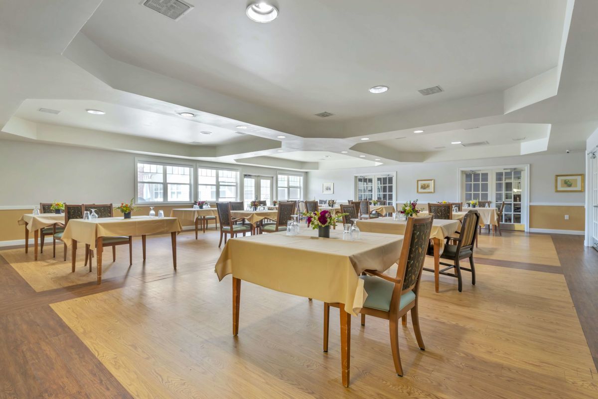 A spacious and well-lit dining room with neatly arranged tables and chairs.