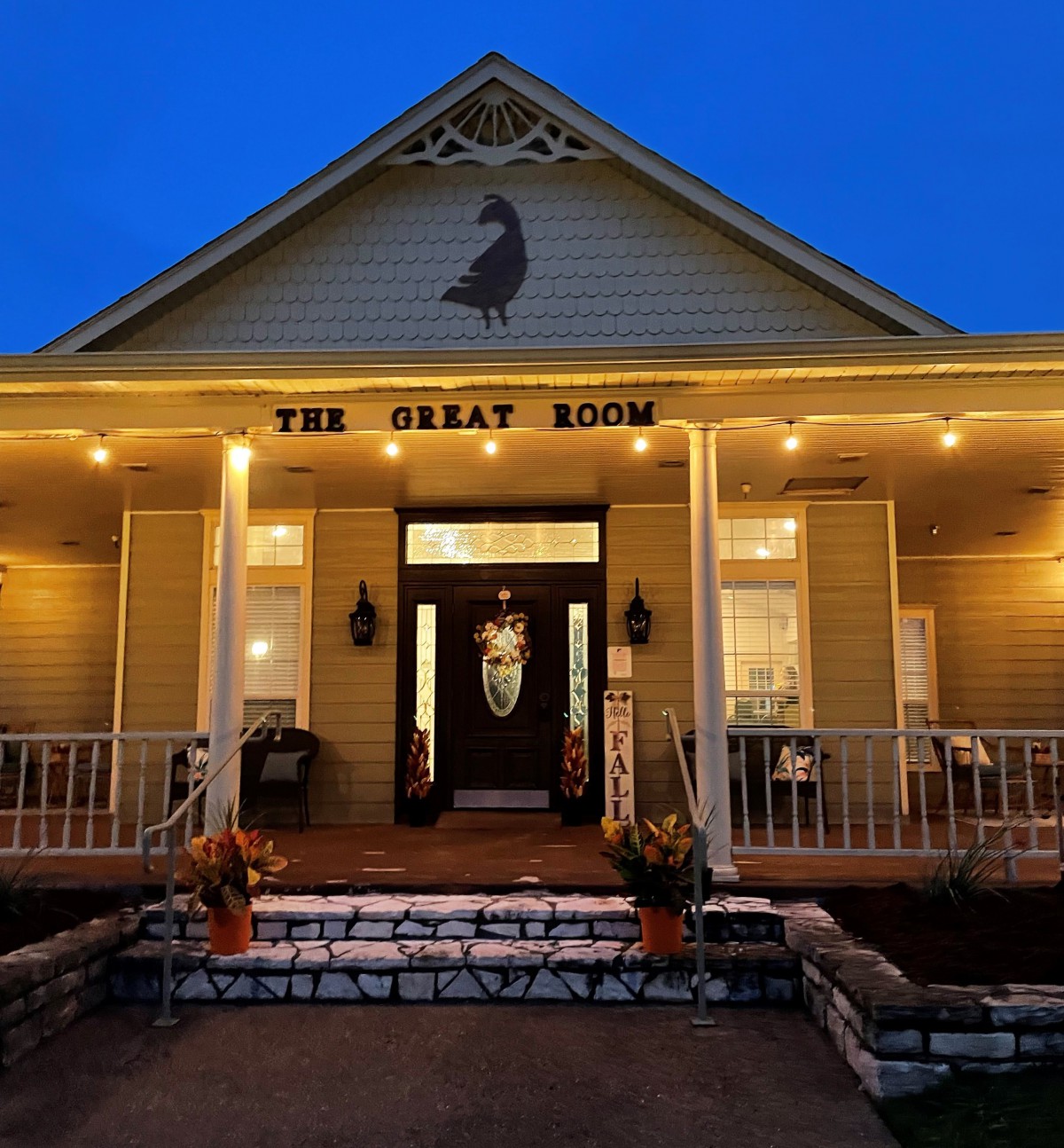 A warmly lit restaurant entrance with a welcoming front porch during nighttime.