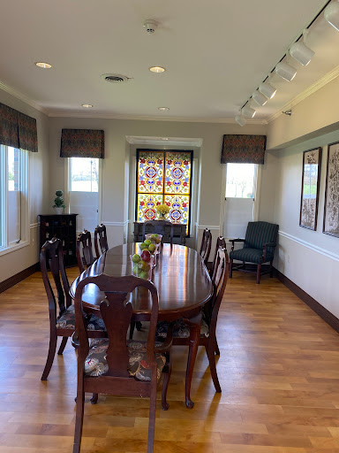 A cozy dining room featuring a wooden table surrounded by chairs and decorative windows.