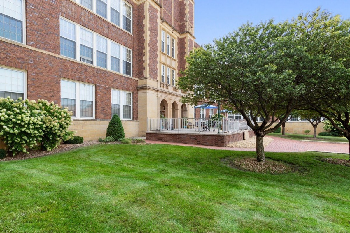 A brick building with a neatly maintained lawn and a tree in front.