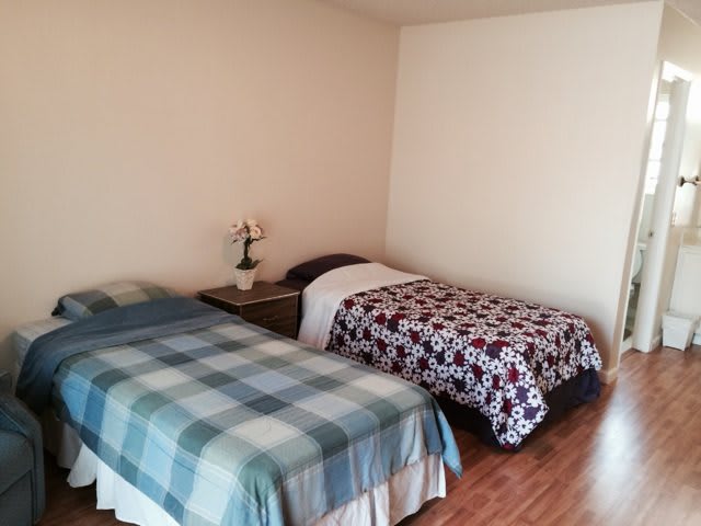 A cozy bedroom featuring two twin beds with different patterns, separated by a small table with a flower vase.