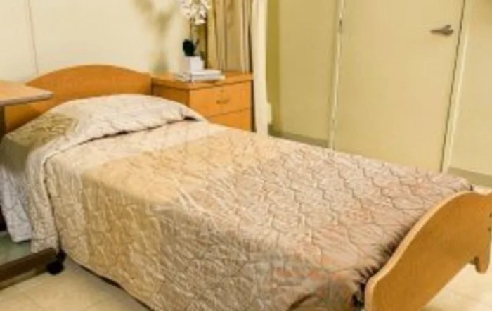 A cozy bedroom with a neatly made single bed and a nightstand.