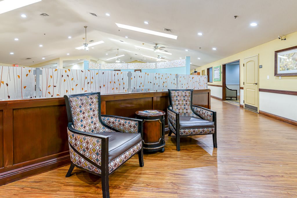 A cozy lounge area featuring two patterned chairs and a small round table on a wooden floor.