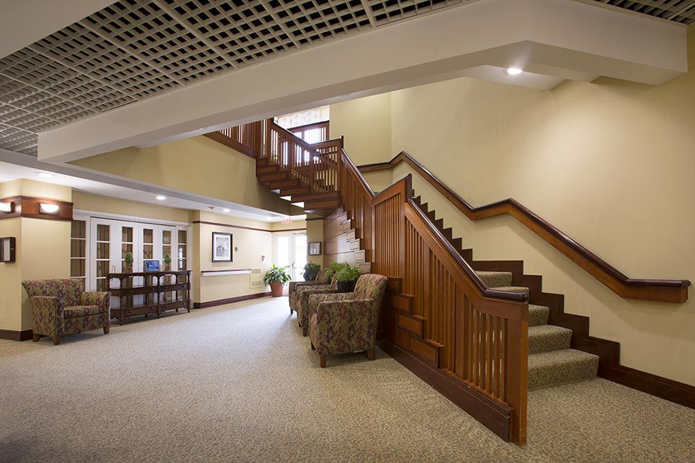 A well-lit lobby area featuring wooden stairs and comfortable seating.