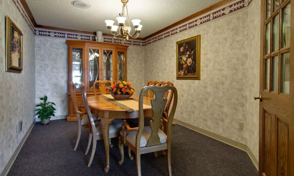A cozy dining room with an elegant wooden table and chairs, adorned by a chandelier and wall art.