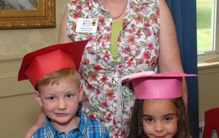 Two children wearing graduation caps pose with an adult.