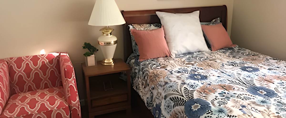 A cozy bedroom setup with a bedside lamp and floral bedding.