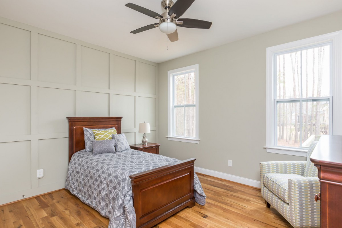 A cozy bedroom with a single bed, featuring wooden floors, modern decor, and large windows that allow natural light to fill the space.
