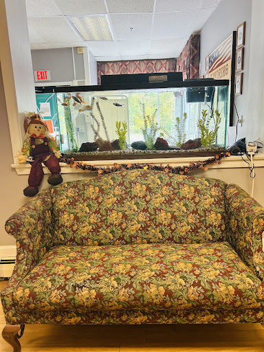 A cozy seating area featuring a floral patterned couch and a vibrant aquarium in the background.