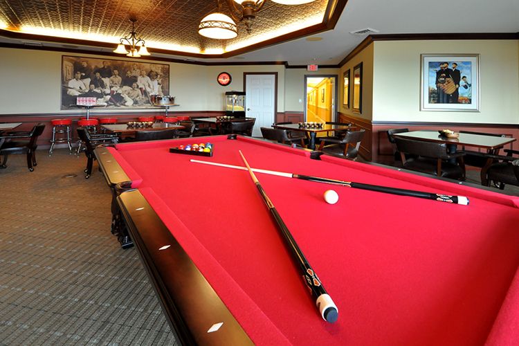 A cozy recreation room featuring a red-felt pool table with cue sticks arranged on top.