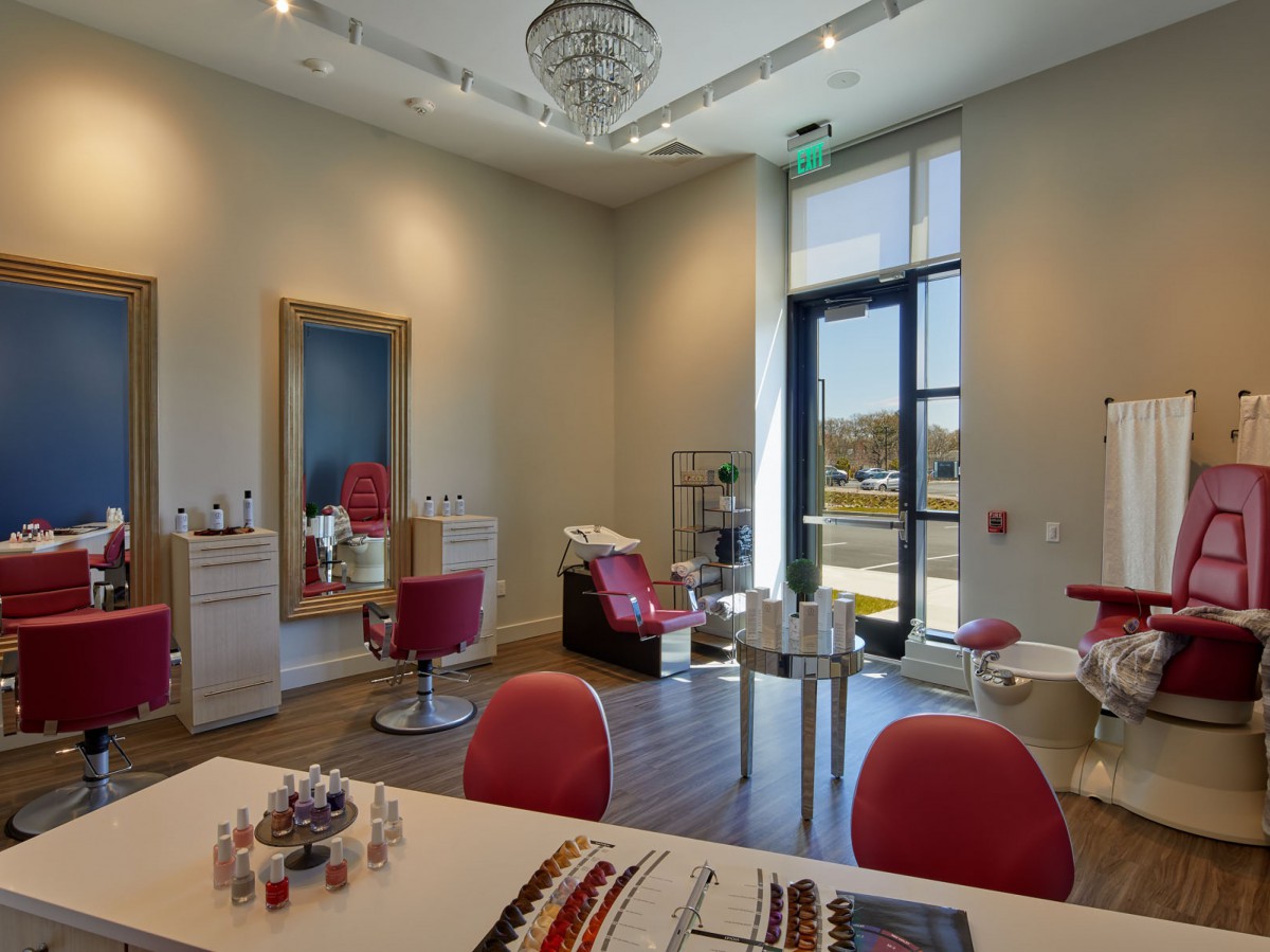 A well-appointed salon interior featuring red chairs, mirrors, and various beauty products.