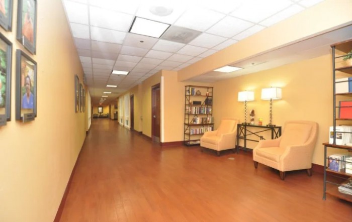 A spacious hallway with wooden flooring and a cozy seating area illuminated by stylish lamps.